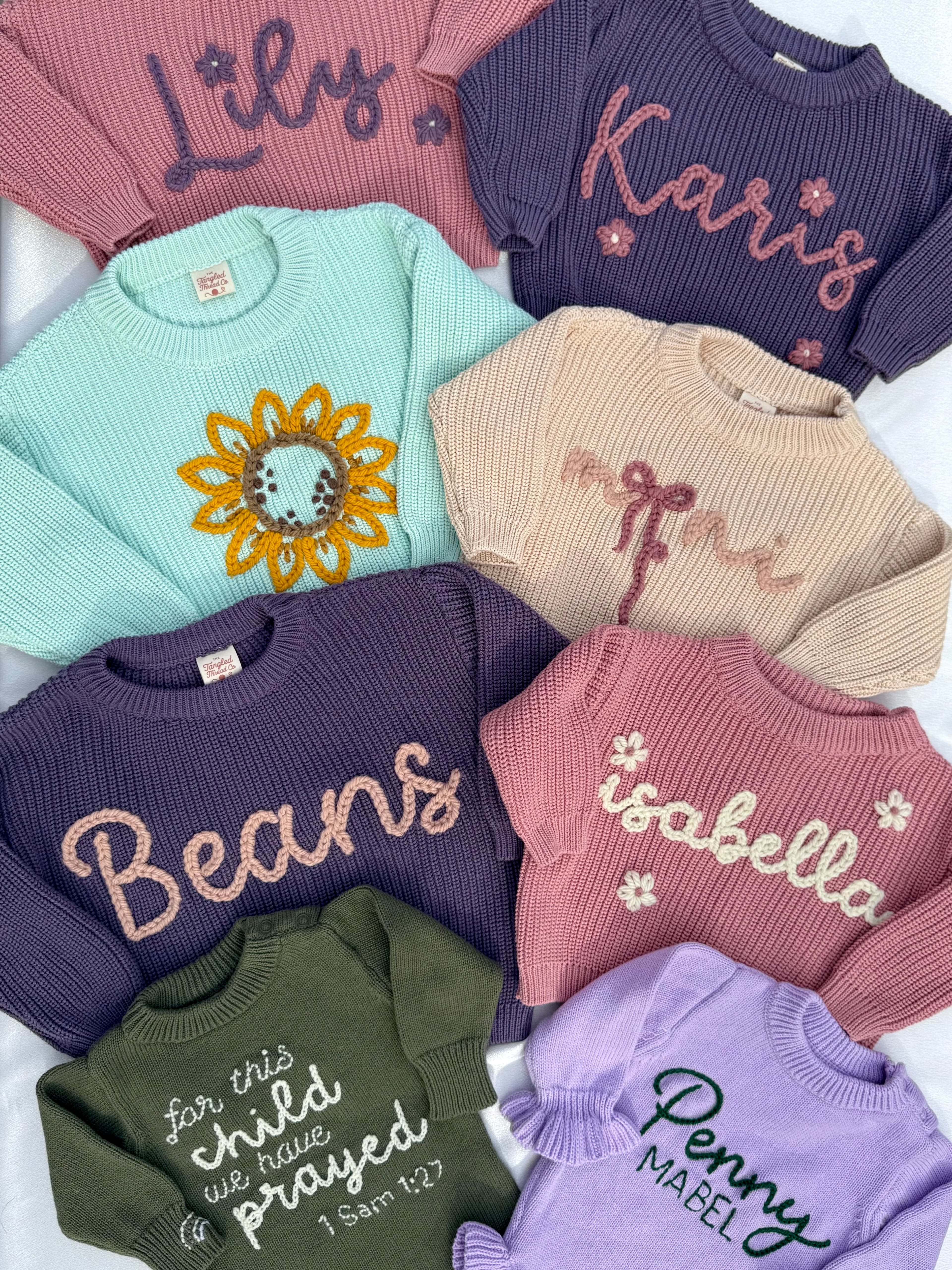 Custom embroidered sweaters laid flat: Lily, Karis, Isabella, Penny Mabel, and more